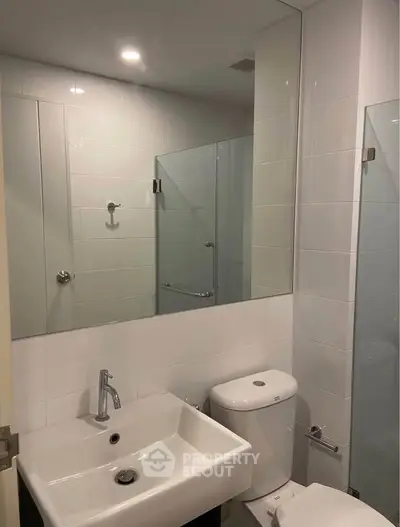 Modern bathroom with sleek fixtures and large mirror in a contemporary apartment.