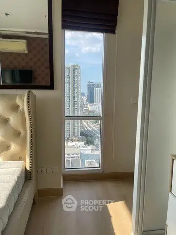 Bright bedroom with city view from large window, featuring elegant bed and modern decor.