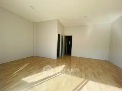 Spacious empty room with wooden flooring and ample natural light, perfect for customization.