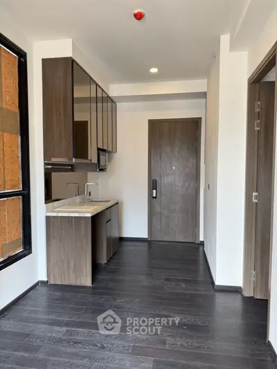 Modern compact kitchen with sleek cabinetry and dark wood flooring