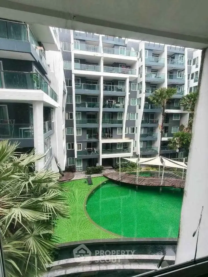 Modern apartment complex with a vibrant green pool and lush palm trees, offering a luxurious urban lifestyle.