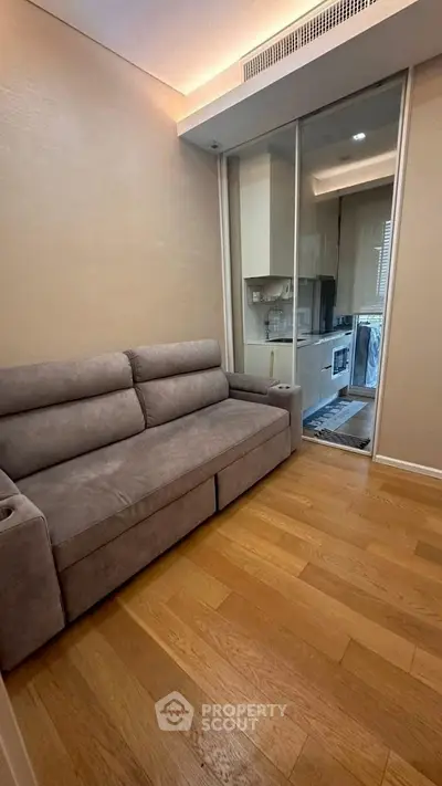 Cozy living room with modern sofa and sliding glass door to compact kitchen