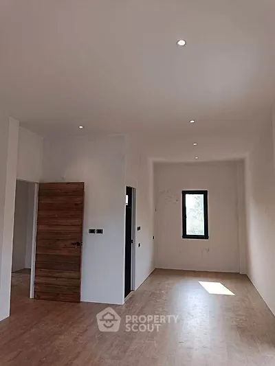 Spacious empty room with wooden door and natural light, ideal for customization.