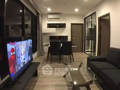 Modern living room with sleek furniture and open layout, featuring a large TV and dining area.