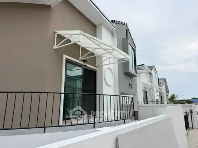 Modern townhouse exterior with stylish balcony and awning, showcasing contemporary architecture.