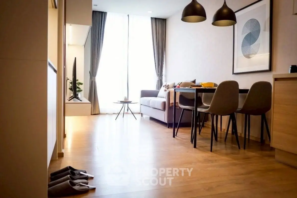 Modern living room with stylish decor and natural light, featuring a cozy sofa and dining area.