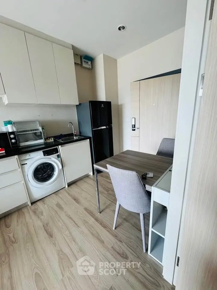 Modern compact kitchen with washing machine and dining area in stylish apartment