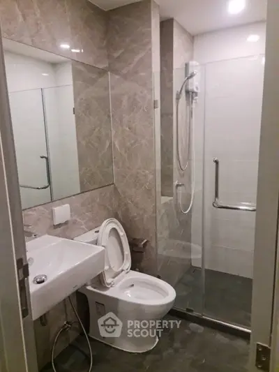 Modern bathroom with glass shower and sleek fixtures in contemporary apartment.