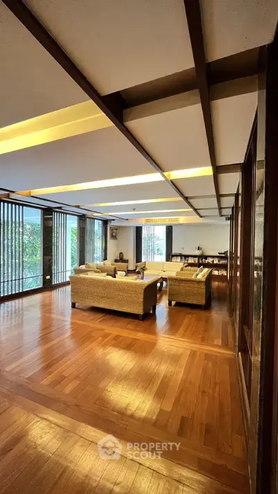 Luxurious living room with wooden flooring and elegant furniture, featuring large windows for natural light.