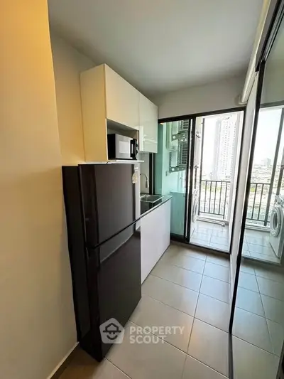 Modern kitchen with sleek appliances and balcony view in urban apartment