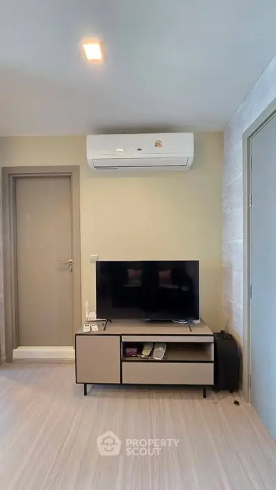 Modern living room with sleek TV setup and air conditioning, perfect for comfortable living.