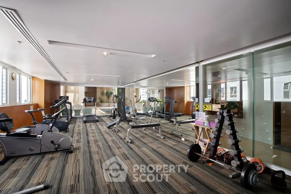 Spacious modern gym with state-of-the-art equipment and large windows for natural light.