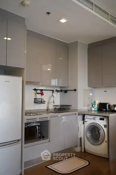 Modern kitchen with sleek appliances and washing machine in a compact layout.