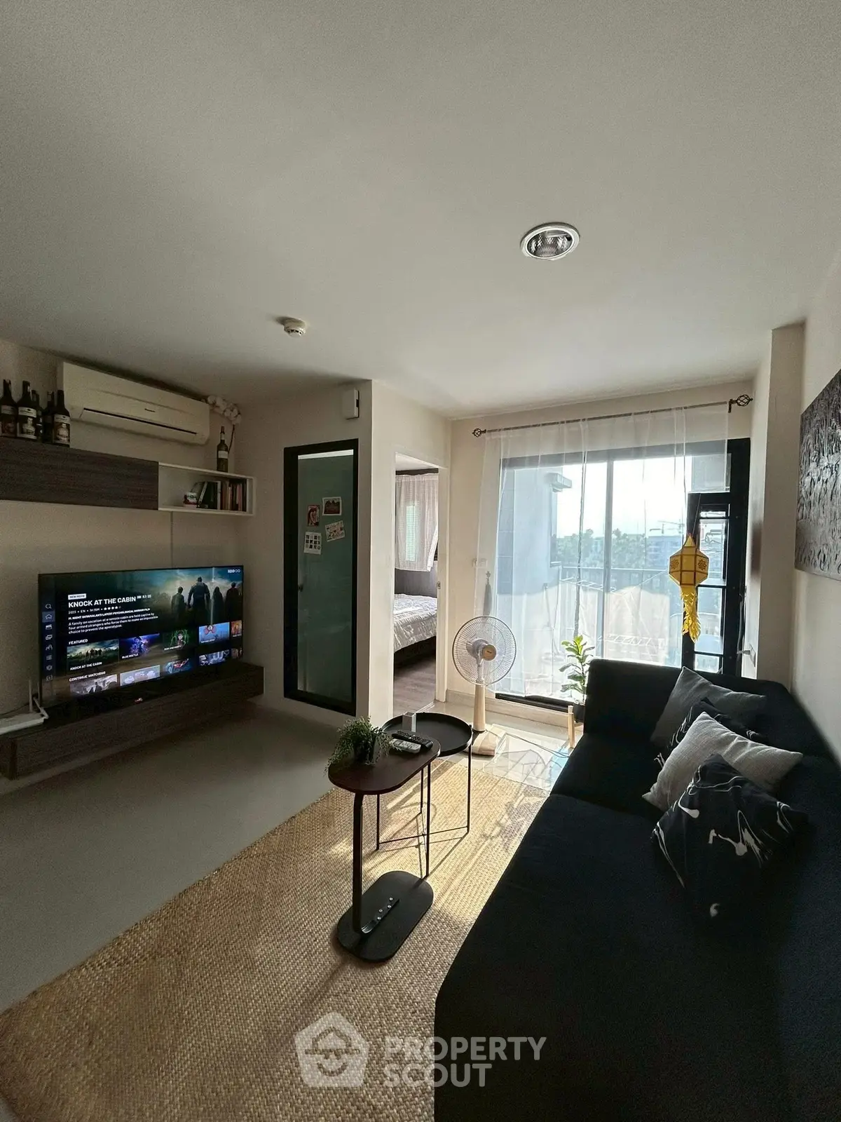 Modern living room with natural light, cozy sofa, and entertainment setup in stylish apartment.