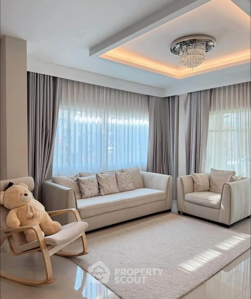 Elegant living room with plush seating and modern chandelier, perfect for relaxation and entertaining.