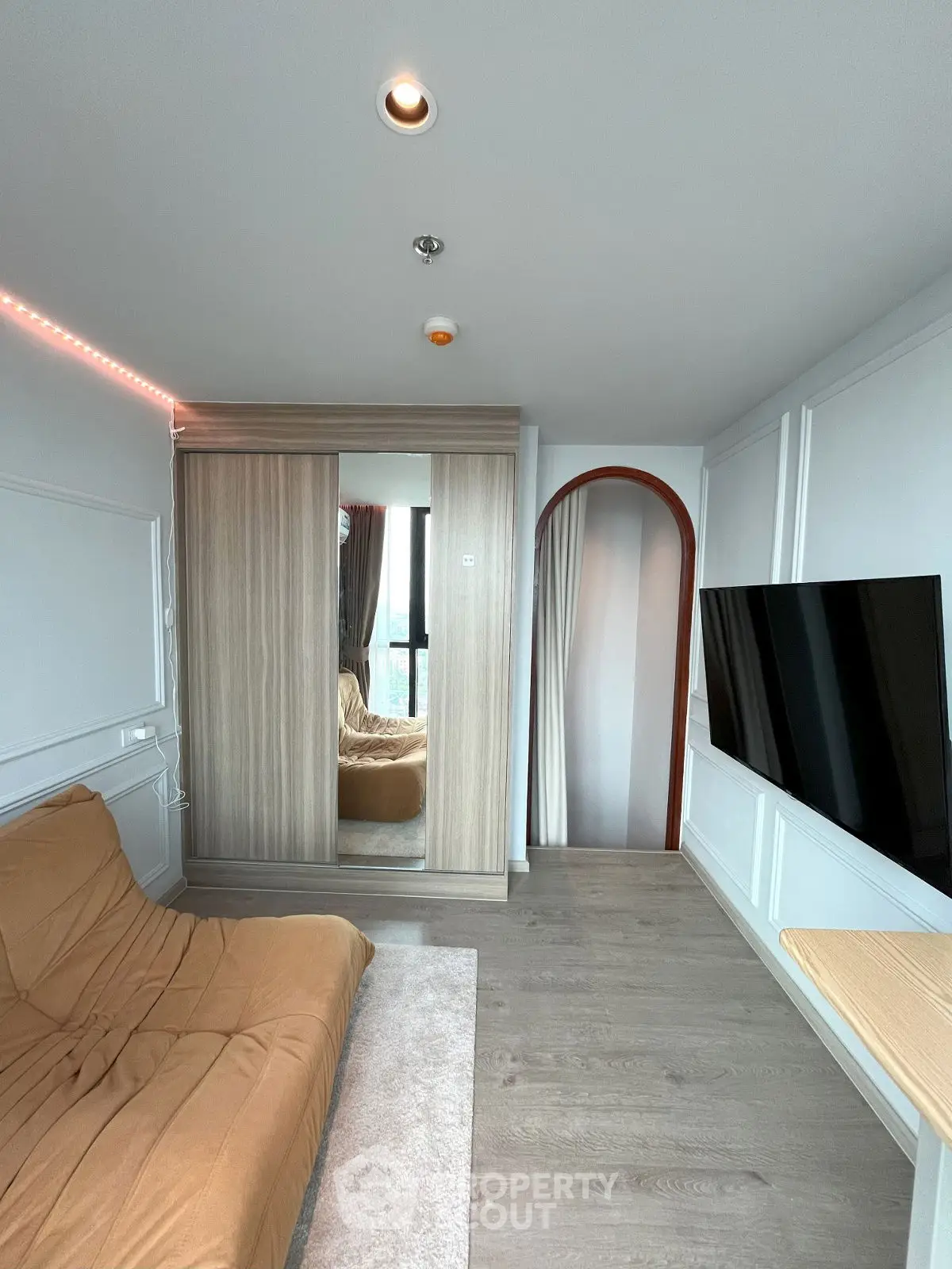 Modern living room with sleek design, featuring a wall-mounted TV and stylish furniture.