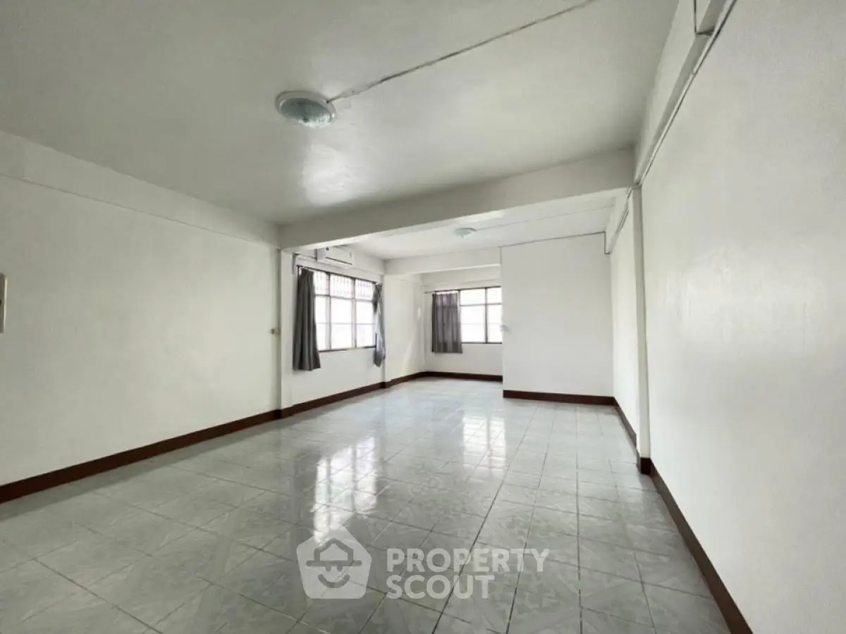 Spacious empty room with tiled flooring and large windows, ideal for customization.