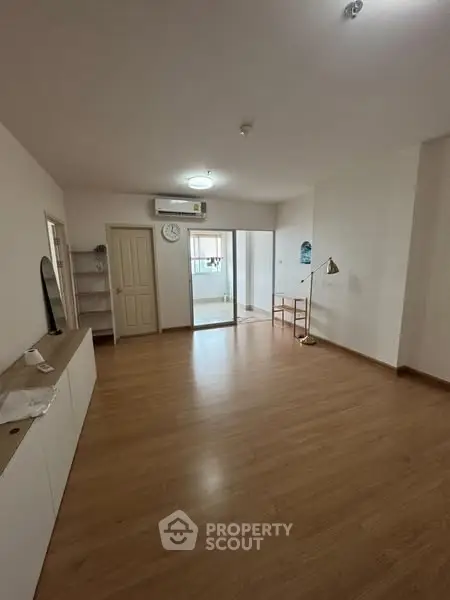 Spacious living room with wooden flooring and modern decor in a bright apartment.