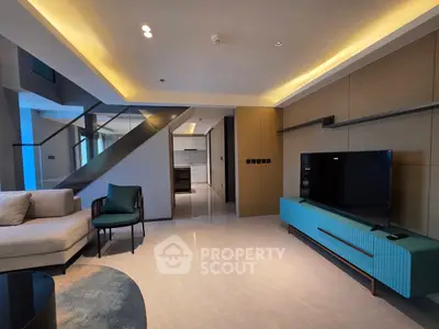 Modern living room with stylish furniture and open layout, featuring a sleek staircase and contemporary design.