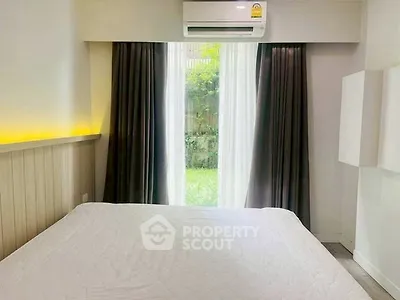Cozy bedroom with large window and garden view, featuring modern air conditioning.
