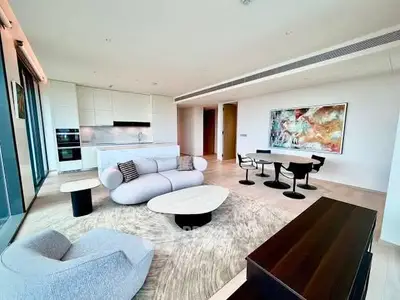 Luxurious modern living room with open kitchen, stylish furniture, and stunning artwork in a high-rise apartment.