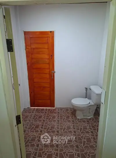 Simple bathroom with tiled floor and wooden door