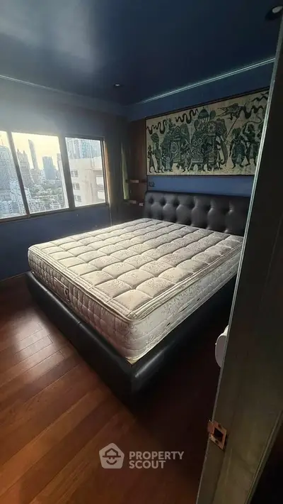 Luxurious bedroom with city view and elegant decor in high-rise apartment.