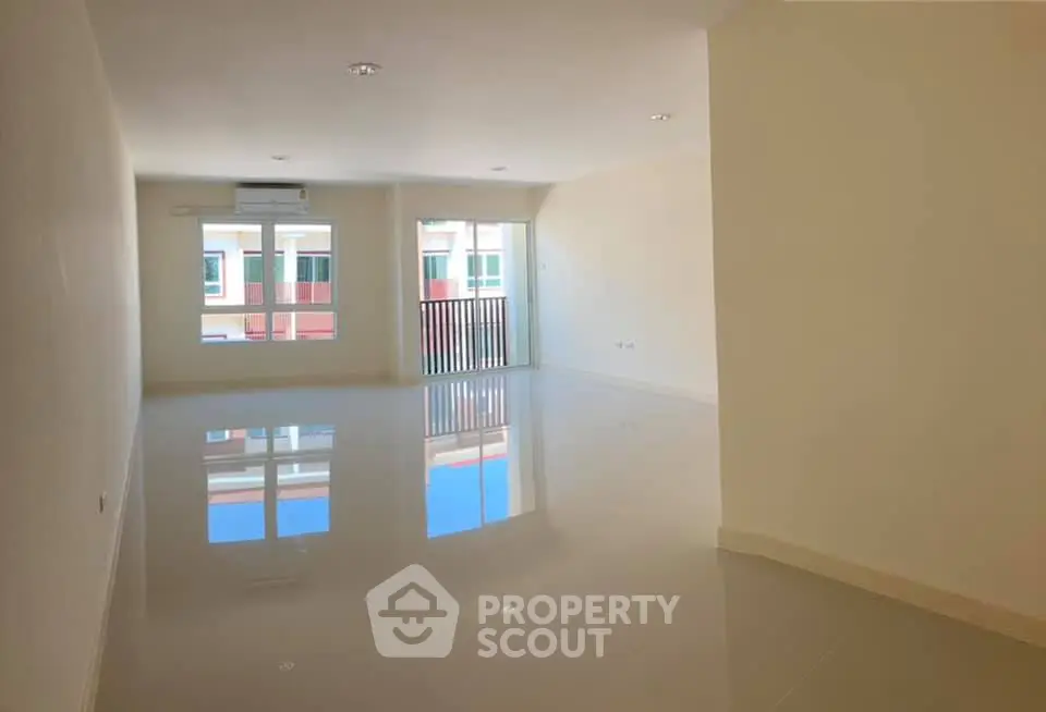 Spacious unfurnished living room with glossy floors and large windows in modern apartment.