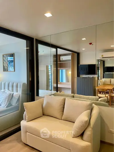Modern living room with cozy beige sofa and mirrored wall reflecting elegant decor.