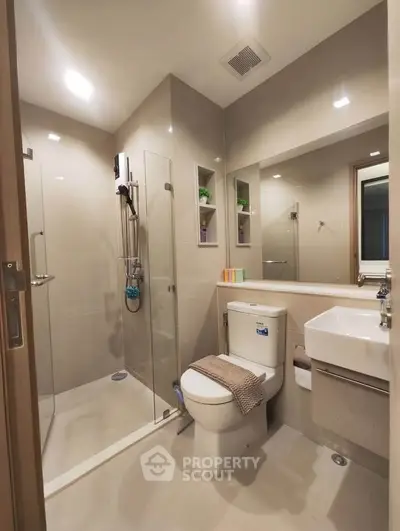 Modern bathroom with glass shower and sleek fixtures in a contemporary apartment.