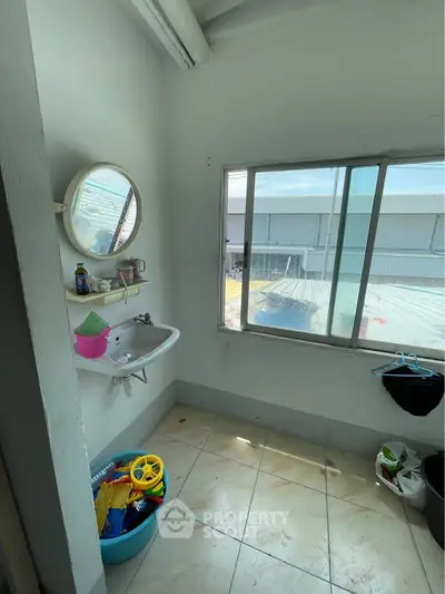 Bright utility room with large window and sink, ideal for laundry or storage.