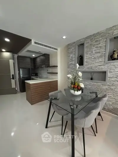 Modern dining area with glass table and stylish kitchen in open layout apartment.