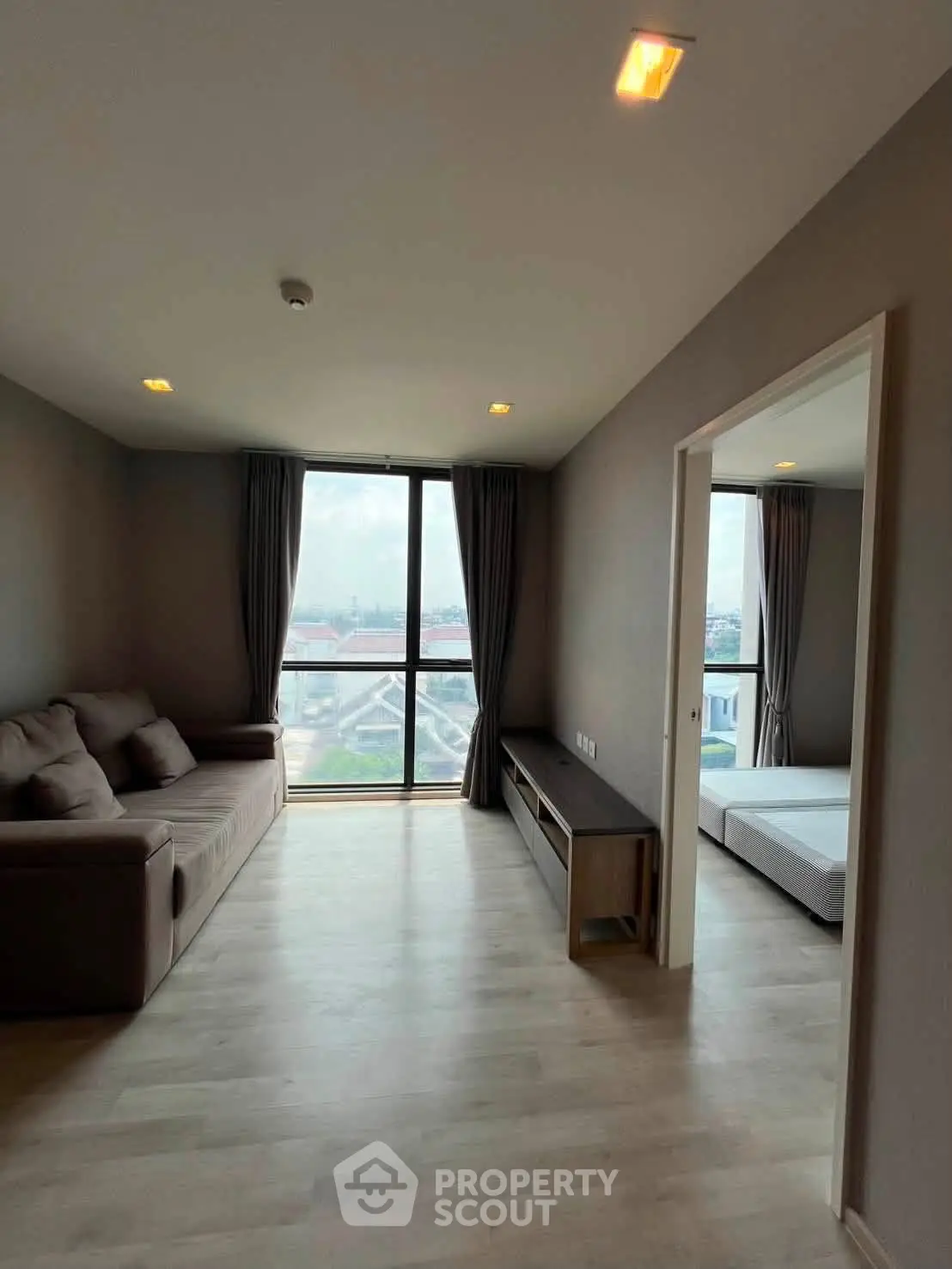 Spacious living room with large window and modern decor in a high-rise apartment.