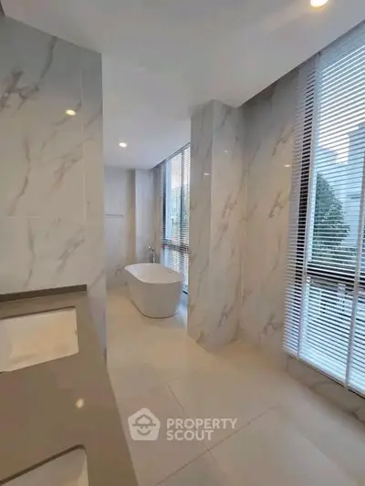 Luxurious marble bathroom with freestanding tub and large windows for natural light.