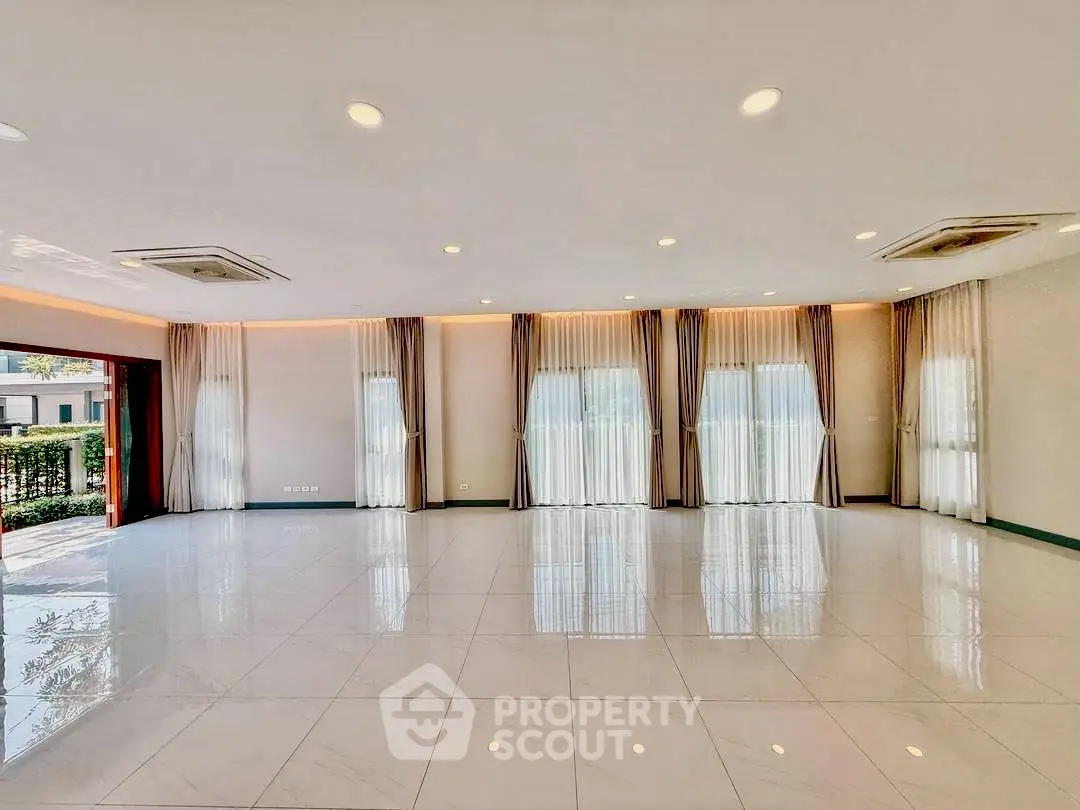 Spacious and elegant living room with large windows and modern lighting