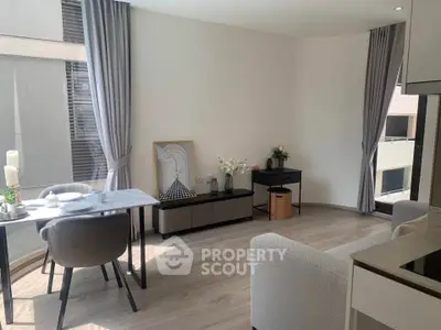 Modern living room with elegant decor and natural light, featuring dining area and stylish furniture.