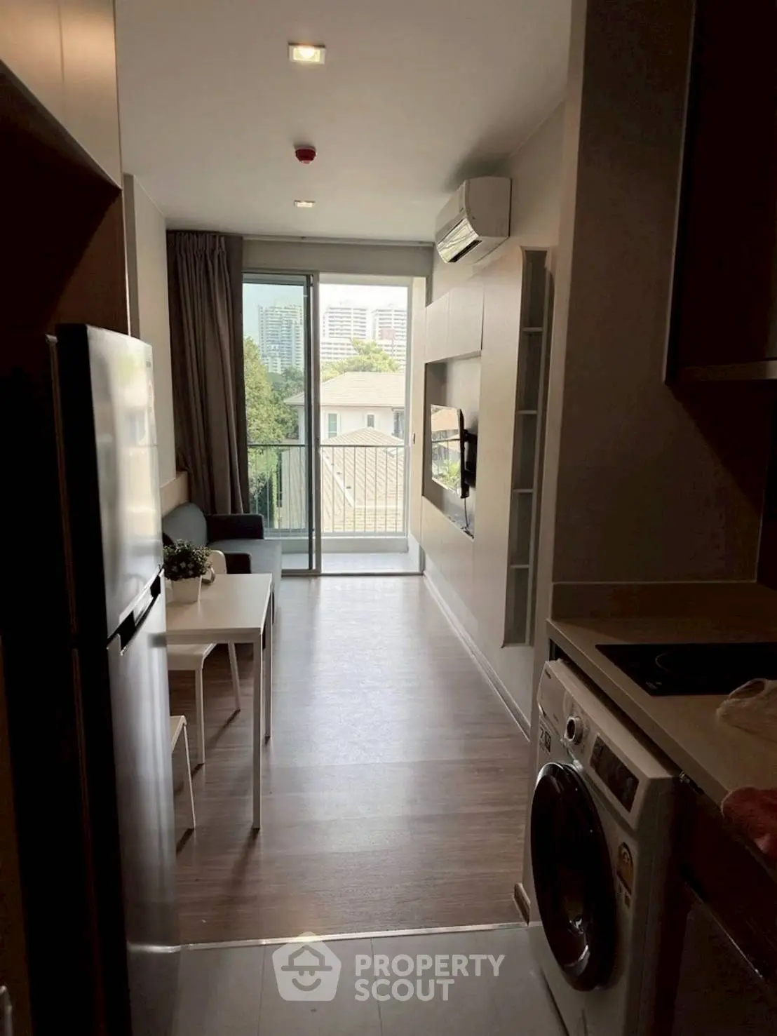 Modern apartment interior with balcony view, featuring sleek kitchen and cozy living area.