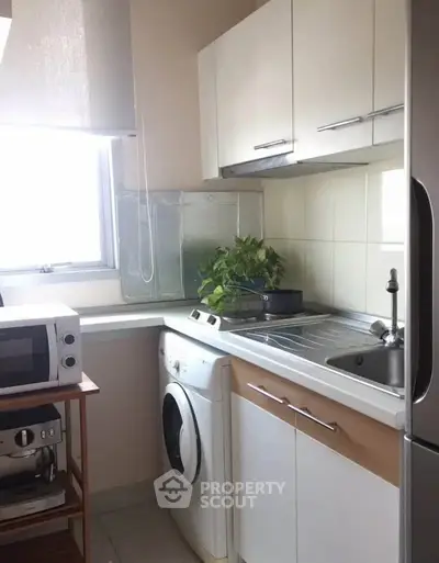 Compact kitchen with washing machine and microwave, ideal for small apartments.