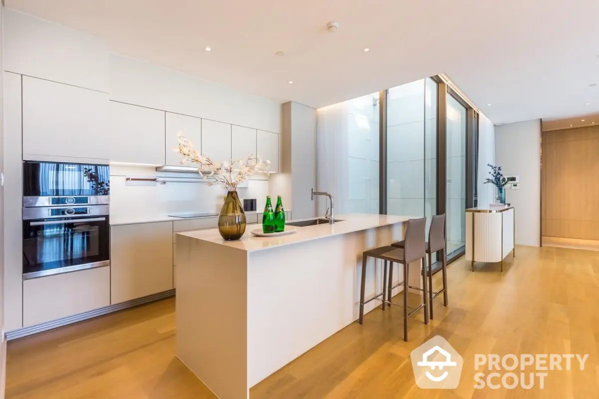 Modern kitchen with sleek design, island seating, and built-in appliances in luxury apartment.