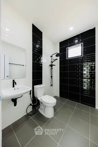 Modern bathroom with sleek black and white tiles and contemporary fixtures.