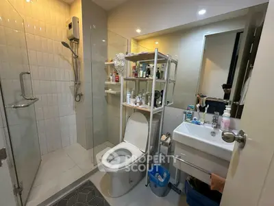 Modern bathroom with shower, toilet, and sink, featuring ample storage and contemporary design.
