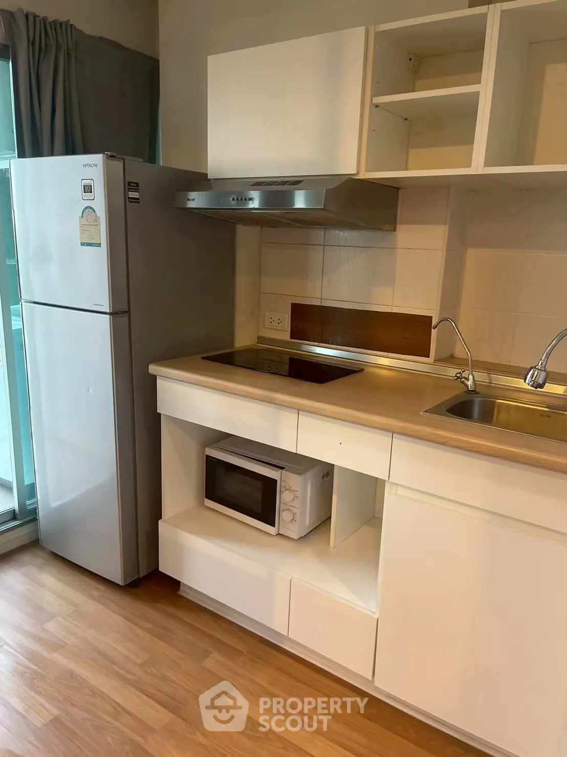 Modern kitchen with sleek cabinets, stainless steel appliances, and wooden flooring in a cozy apartment.
