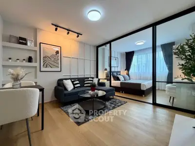 Modern open-plan living room with stylish decor and glass partition to bedroom