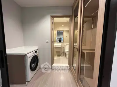 Modern laundry area with washing machine and mirrored closet in sleek apartment.