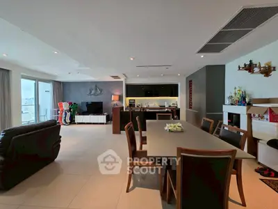 Spacious modern living room with open kitchen and dining area, featuring sleek furniture and ample natural light.