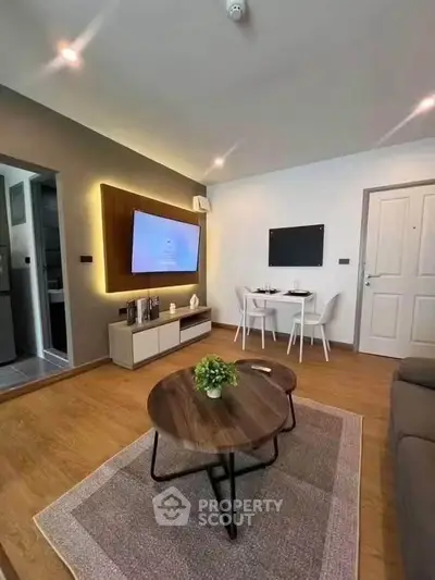 Modern living room with stylish decor and dining area, featuring a wall-mounted TV and wooden flooring.