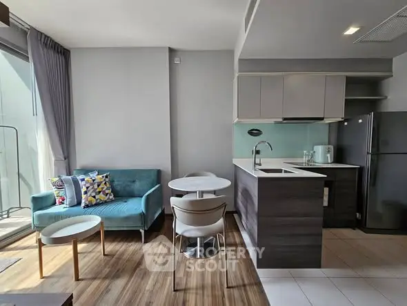 Modern open-layout living room with kitchen, featuring stylish furniture and natural light.