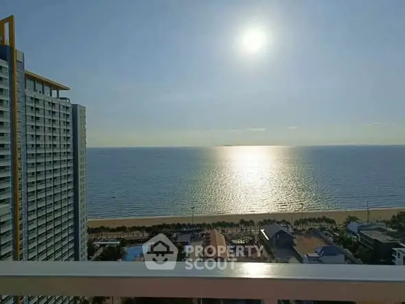 Stunning ocean view from high-rise balcony with sunlit sea and beach panorama.