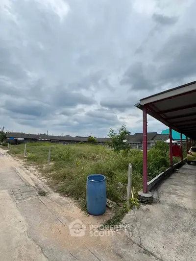 Vacant land plot with potential for development in a residential area under a cloudy sky.