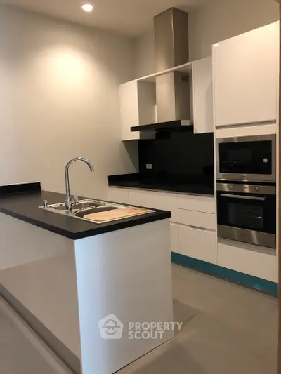 Modern kitchen with sleek black countertops and built-in appliances in a contemporary apartment.